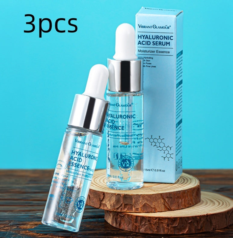 Two bottles of hyaluronic acid serum with a box on a wooden surface against a blue background