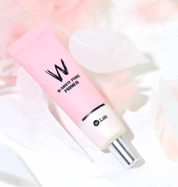 Pink and white cosmetic primer bottle with 'W' branding on a soft, blurred background